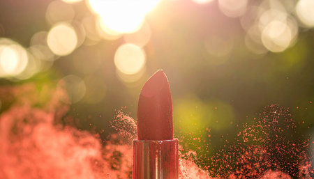 Red lipstick with red powder exploding around it against a bokeh background Clear details and vibrant colors ...の素材