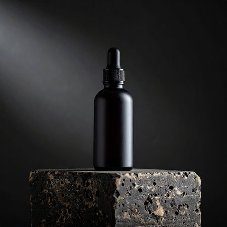 A matte black dropper bottle with a ribbed cap sits on a porous stone block Clear details and vibrant colors ...の素材