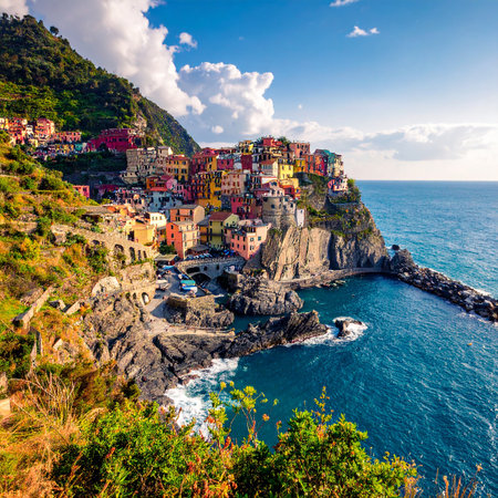 Colorful Italian village on a cliff overlooking the sparkling blue sea with lush green hills.の素材
