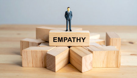 A miniature businessman stands atop wooden blocks that spell out the word EMPATHY.の素材