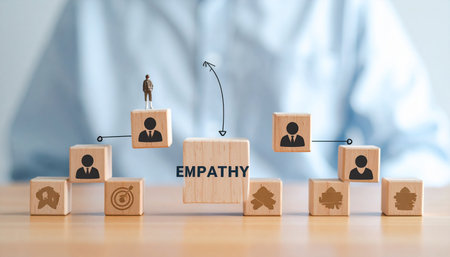 Wooden blocks spell EMPATHY with figurines and icons showing connection and goals.の素材