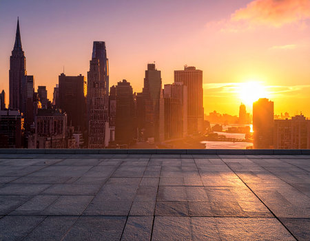 A New York City skyline at sunset with a paved rooftop in the foreground and golden light.の素材