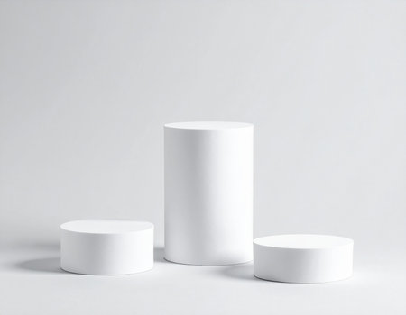 Three white cylindrical pedestals of different heights are arranged on a plain white background.の素材