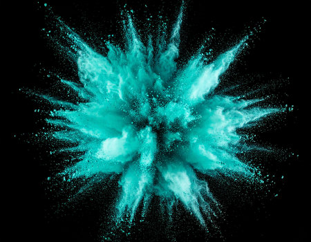 A radial explosion of teal powder creates a vibrant burst against a black background.の素材