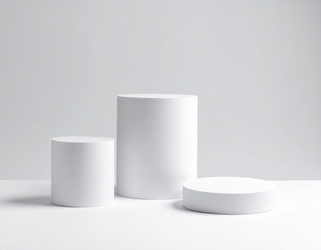 Three white cylindrical pedestals of different heights are placed on a white surface.の素材