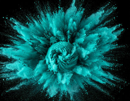 A vibrant teal powder explosion bursts outward in a dynamic cloud against a black background.の素材