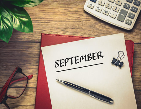 The word september is written in a notebook on a desk.の素材