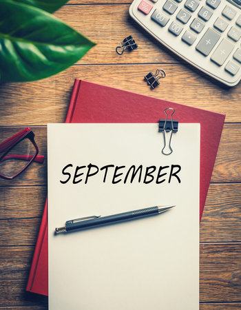 SEPTEMBER word on paper with calculator and eyeglasses on tableの素材
