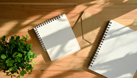Notebook on a wooden table with plant. 3d rendering.の素材