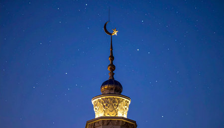 Crescent moon over the dome of the mosque at night with a starry skyの素材