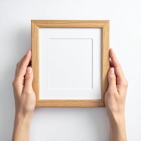 Wooden photo frame in female hands on white background, top viewの素材