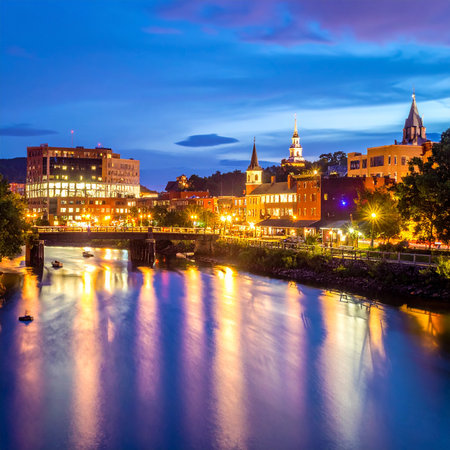Evening showing illuminated cityscape at dusk reflecting on calm water with distant hills and cloudy sky keywords: city, cityscape, dusk, twilight,...の素材