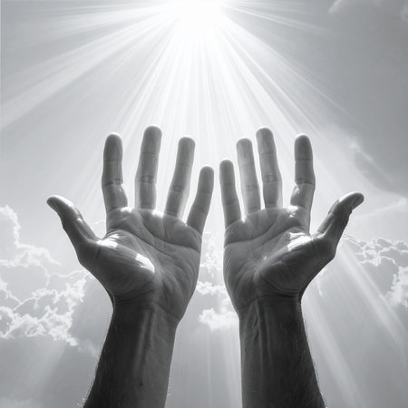 Two human hands are held open and reaching upwards towards a brilliant sun with strong rays, against a cloudy sky.の素材