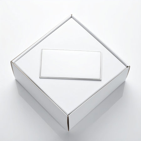 A top-down angled view of a closed white cardboard box with a blank rectangular label on its lid, set against a white background.の素材