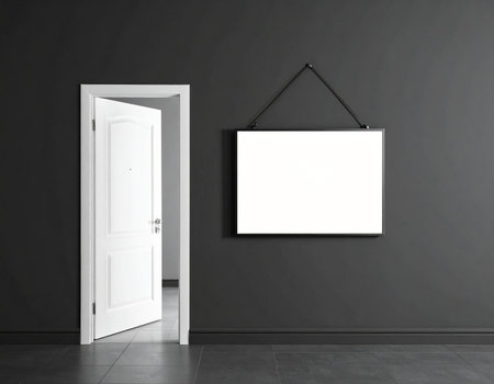 An open white door reveals a glimpse of another room, next to a dark gray wall with a blank horizontal sign hanging above a dark tiled floor.の素材