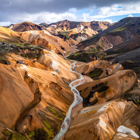 Aerial view of a dramatic mountain valley with a winding river and a cloudy sky. Clear details and vibrant col...の素材
