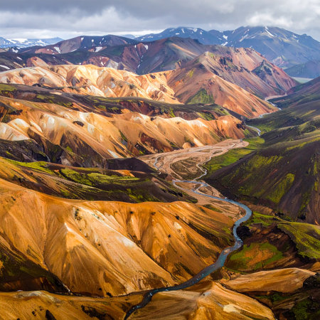 Aerial view of expansive Icelandic highlands featuring colorful mountains and a winding river.の素材