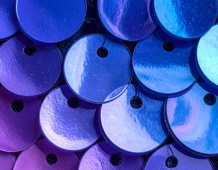 Extreme close-up of round, iridescent sequins in blue and purple hues, showing individual holes for attachment and a textured surface.の素材