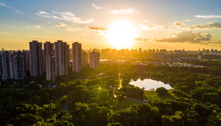 An aerial view captures a city park and apartment buildings illuminated by the warm, golden light of the setting sun.の素材