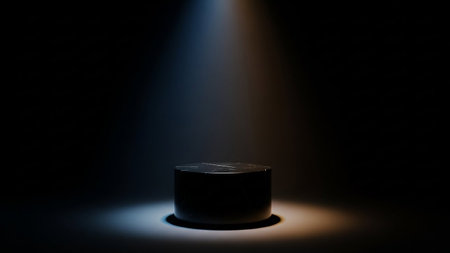 A dark marble cylindrical pedestal is lit by a moody spotlight with blue and orange hues, creating a dramatic effect on a dark background.の素材