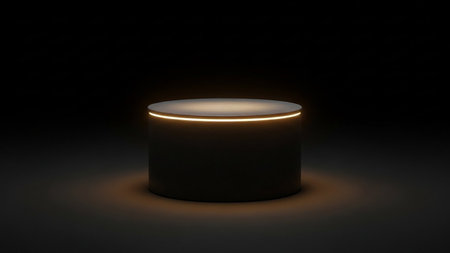 A dark cylindrical pedestal features a warm golden light ring around its top edge, illuminated in a dim studio.の素材