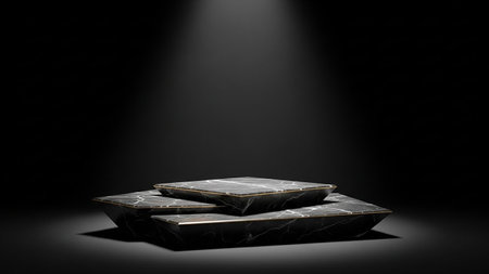 Stacked black marble pedestals with gold trim are lit by a spotlight against a dark studio background.の素材