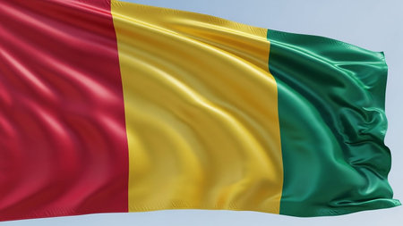 The national flag of Guinea, featuring bold vertical stripes of red, yellow, and green, waves dynamically in the wind.の素材