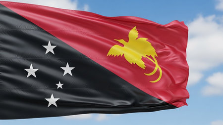 The flag of Papua New Guinea, with its diagonal red and black fields and yellow bird of paradise, waves in the sky.の素材