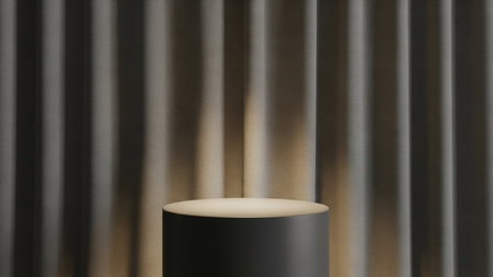 A dark grey cylindrical display stand is softly illuminated by warm light against a backdrop of textured grey vertical curtains.の素材