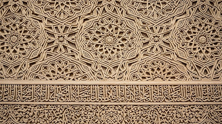 An ancient stone wall intricately carved with complex geometric patterns and a band of detailed Arabic calligraphy below.の素材