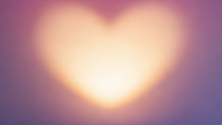 A soft focus heart shape glows with warm light against a blurred purple and pink background.の素材