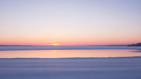 A tranquil winter sunset casts pastel hues over a frozen lake and snow-covered ground.の素材