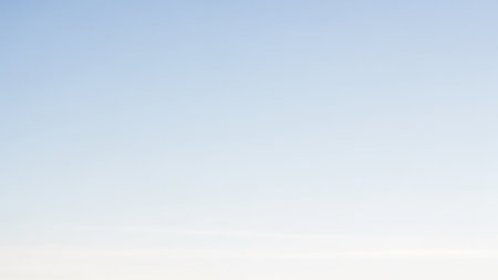 A clear, pale blue sky with a subtle gradient from the horizon upwards, offering a serene backdrop.の素材