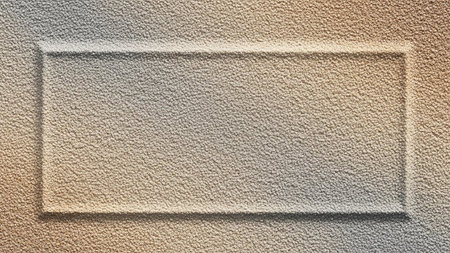 A rectangular frame is embossed into a textured beige surface, casting a subtle shadow and creating a recessed area.の素材