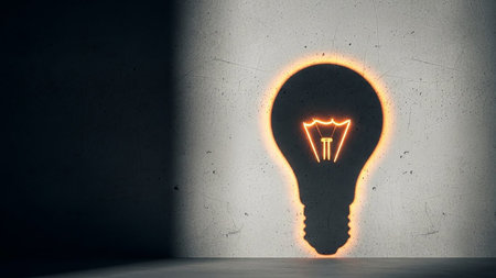 A glowing light bulb silhouette casts a shadow on a textured concrete wall, symbolizing an idea.の素材