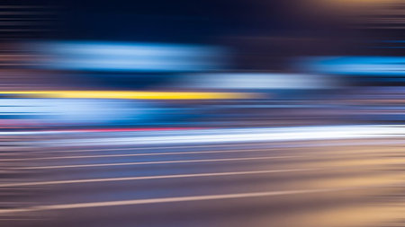 Abstract motion blur of colorful city lights and traffic streaks at night, conveying speed.の素材