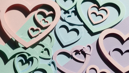 Overlapping pastel paper hearts in shades of pink, mint green, and lavender create a textured, layered backgroundの素材