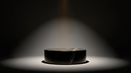 Black showing dark cylindrical marble pedestal illuminated by a dramatic spotlight in a dimly lit studio setting keywords: pedestal, display,...の素材