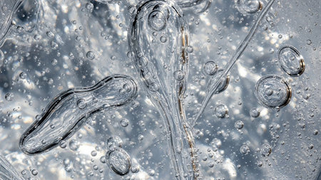 Abstract macro shot of clear gel with trapped air bubbles and swirling translucent forms, creating a dynamic...の素材
