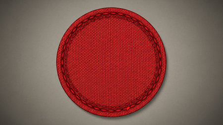 showing red fabric circle emblem with detailed stitching on a textured gray background. resolution use.の素材