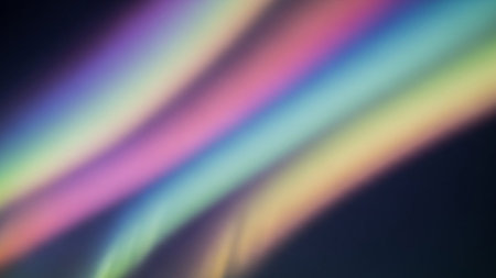 A blurred abstract background featuring soft, diagonal streaks of rainbow-colored light against a dark backdrop.の素材