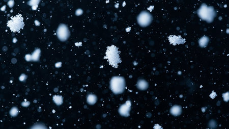 A dark blue background filled with numerous falling snowflakes and soft, out-of-focus white bokeh lights, creating a wintery atmosphere.の素材