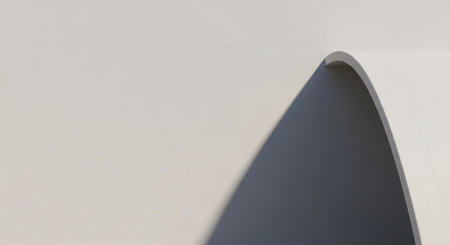 A smooth architectural curve casts a sharp shadow on a minimalist light-colored wall.の素材