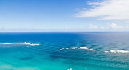 Water showing vast expanse of deep blue ocean water with gentle white waves and a clear bright blue sky above with scattered white clouds.の素材