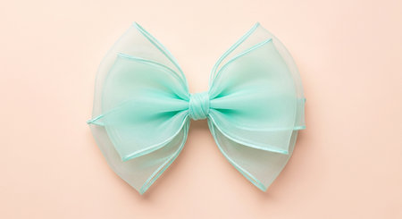 A delicate mint green organza bow with layered petals on a pastel pink background.の素材