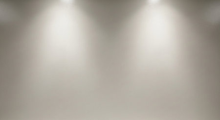 Two soft light beams illuminate a neutral gray wall from above creating a subtle glow.の素材