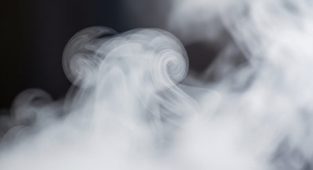Abstract swirling patterns of white smoke or vapor against a dark, out-of-focus background.の素材