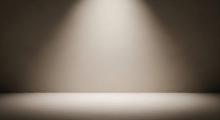 An empty studio room with a warm spotlight shining down on the floor and wall, creating a neutral backdrop.の素材