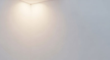 Soft warm light illuminates the corner of a plain white room, creating a gentle gradient of light.の素材