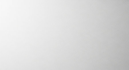 A close-up of a white textured wall with a subtle light gradient and diffused shadows.の素材
